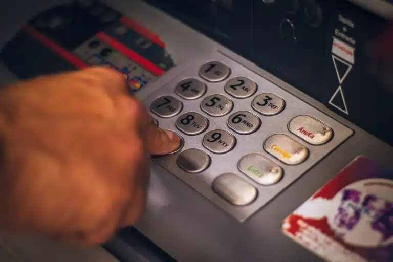 person holding white and red card on a cash dispenser symbolise PCI PIN