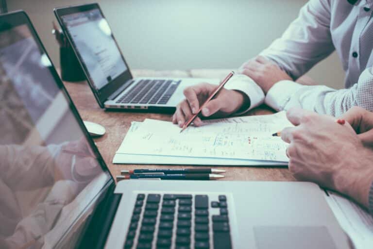 person holding pencil near laptop computer taking note of a pci dss assessment meeting