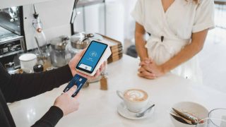 woman standing and holding smartphones linking credit card to phone, PCI P2PE related